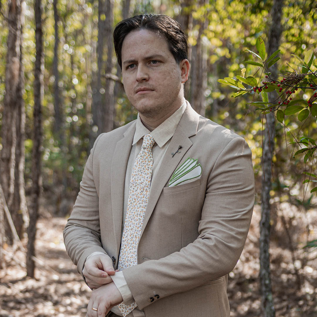 Groom wearing Tan suit and Floral Marigold Yellow Wedding Tie in wooded area