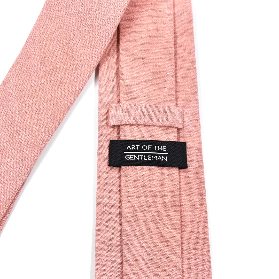 Pink tie with a label reading 'Art of the Gentleman' on a white background