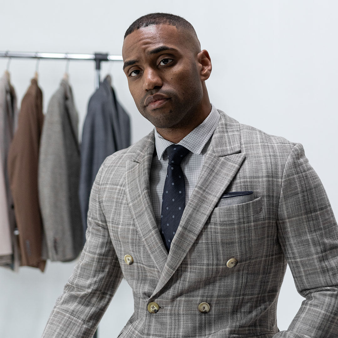 Man wearing a patterned grey suit with polka dot blue tie