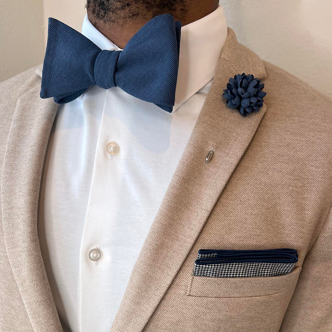 Man wearing solid marine navy bow tie set with a tan suit