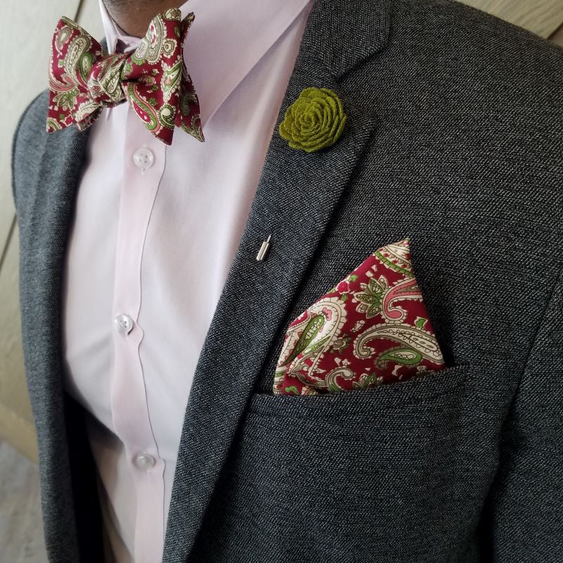 Paisley Scarlet Shamrock cotton pocket square worn with a grey suit jacket, a pink shirt, a bow tie and a lapel pin