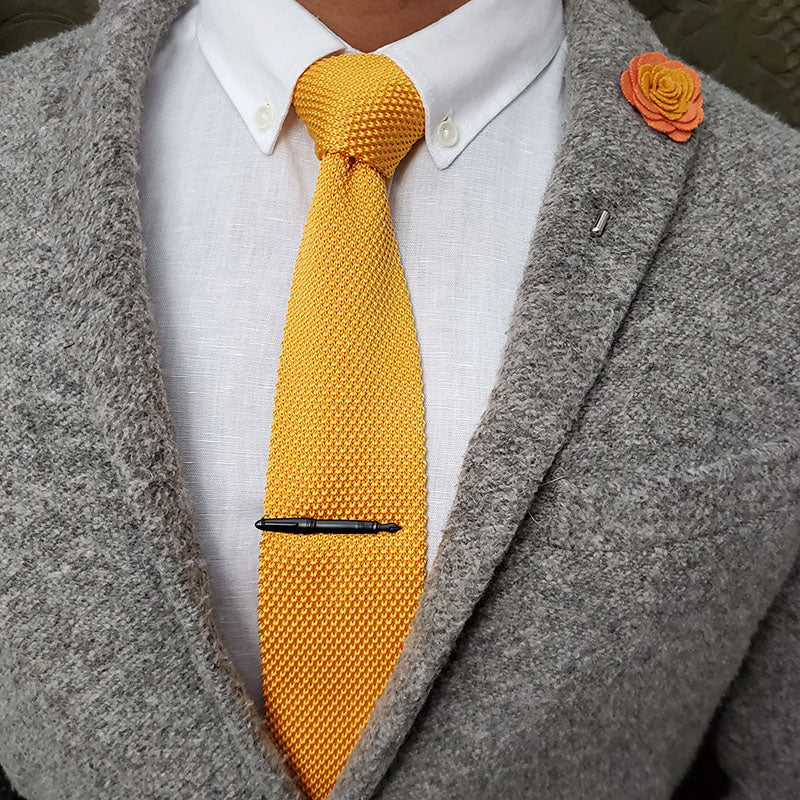 A gentleman posing for a picture with a tie and tie bar.