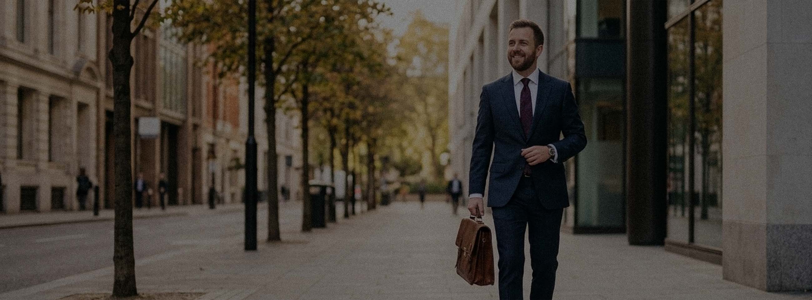Man on a city street lined with trees wearing a business suit