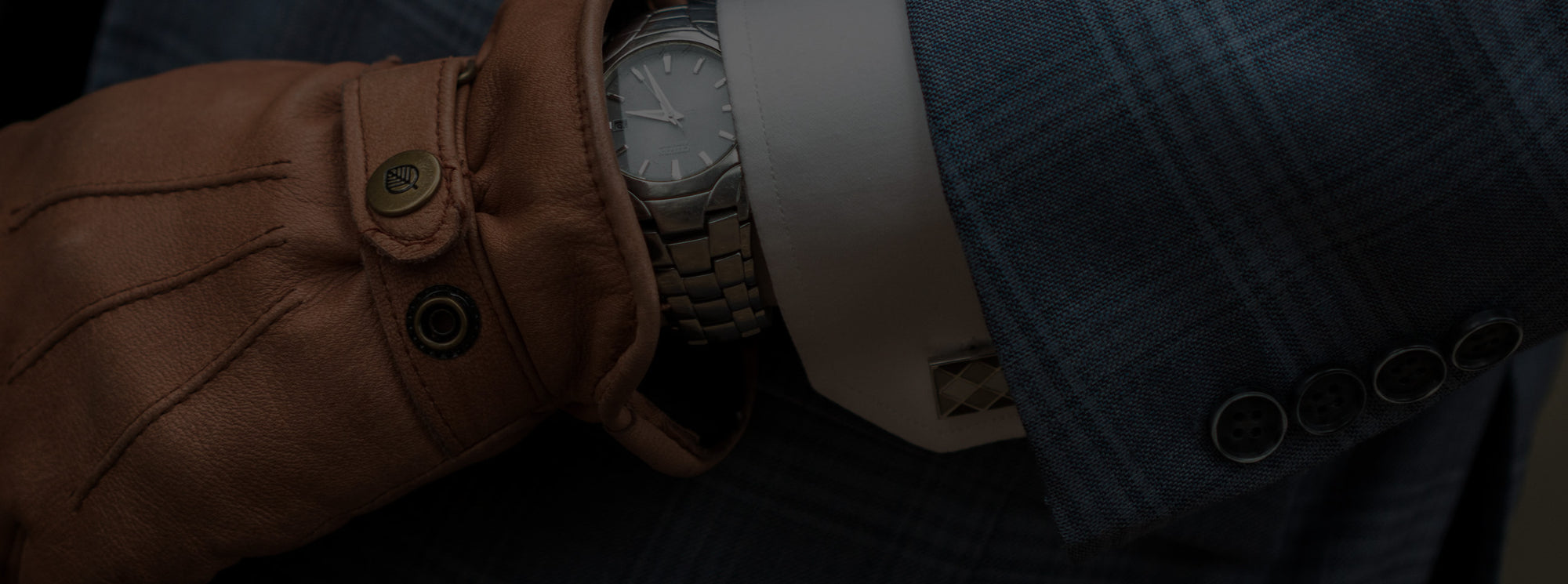Cufflink on a shirt sleeve with a suit and brown golves