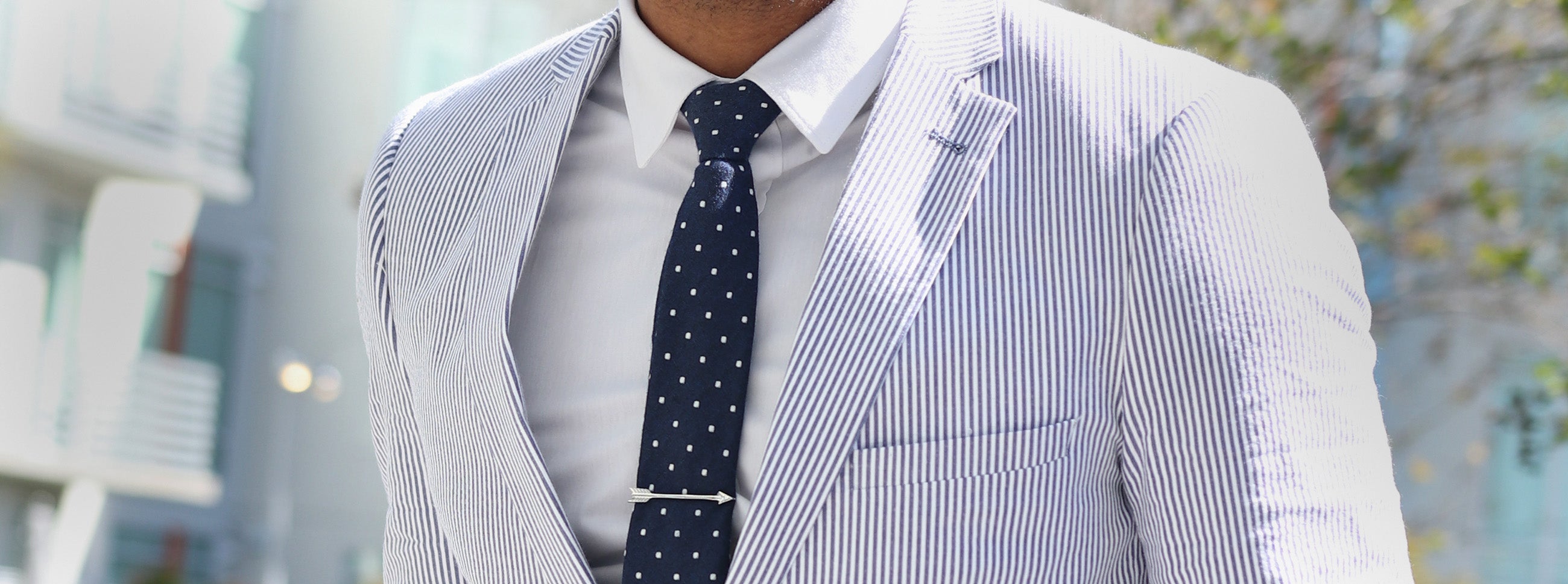 Man wearing a seersucker suit with a blue polka dot tie