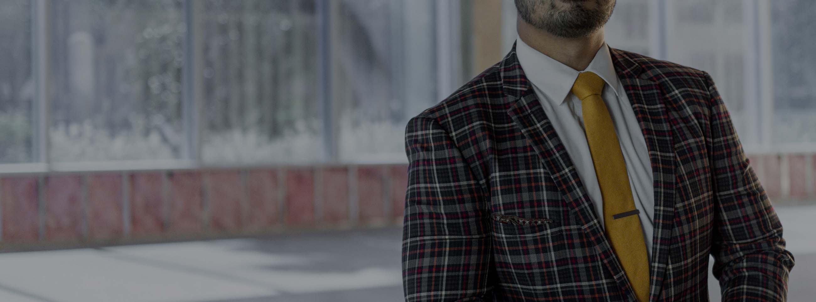 Man wearing a bright plaid suit and dijon yellow tie in an industrial building