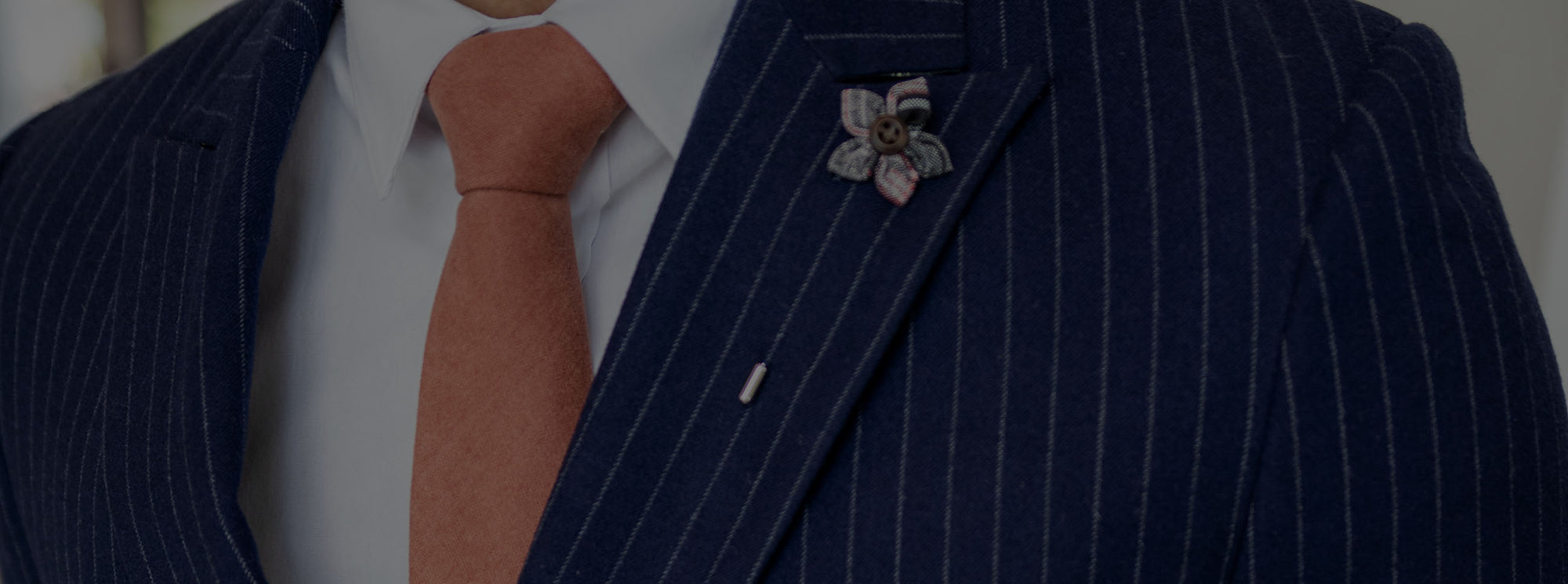 Navy suit with a plaid patterned lapel pin