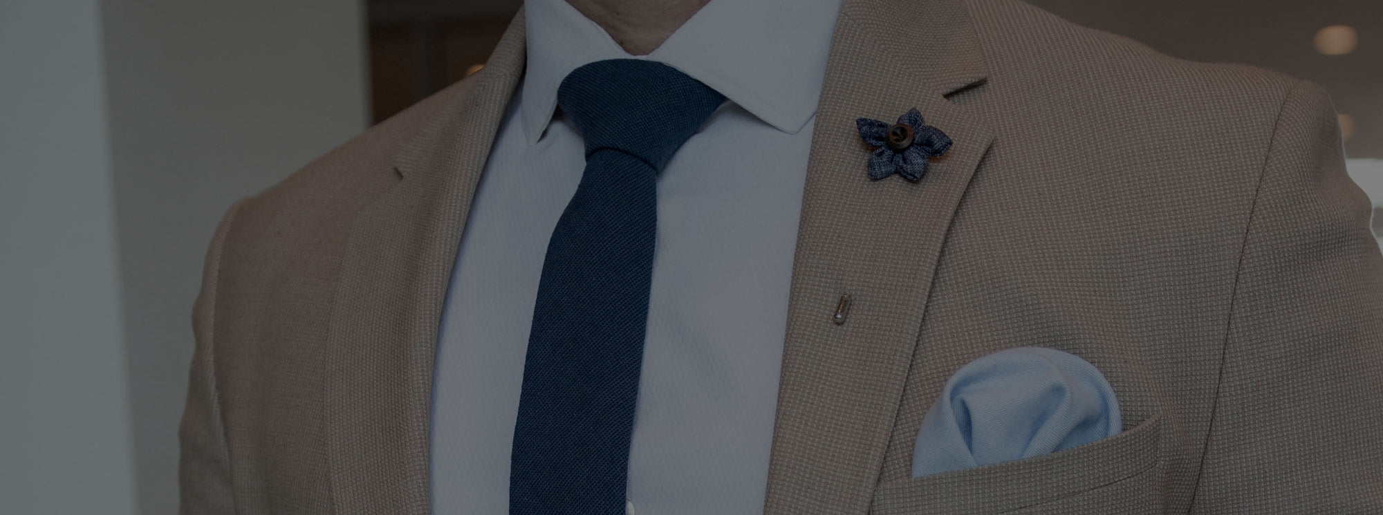 Tan suit with a blue lapel pin