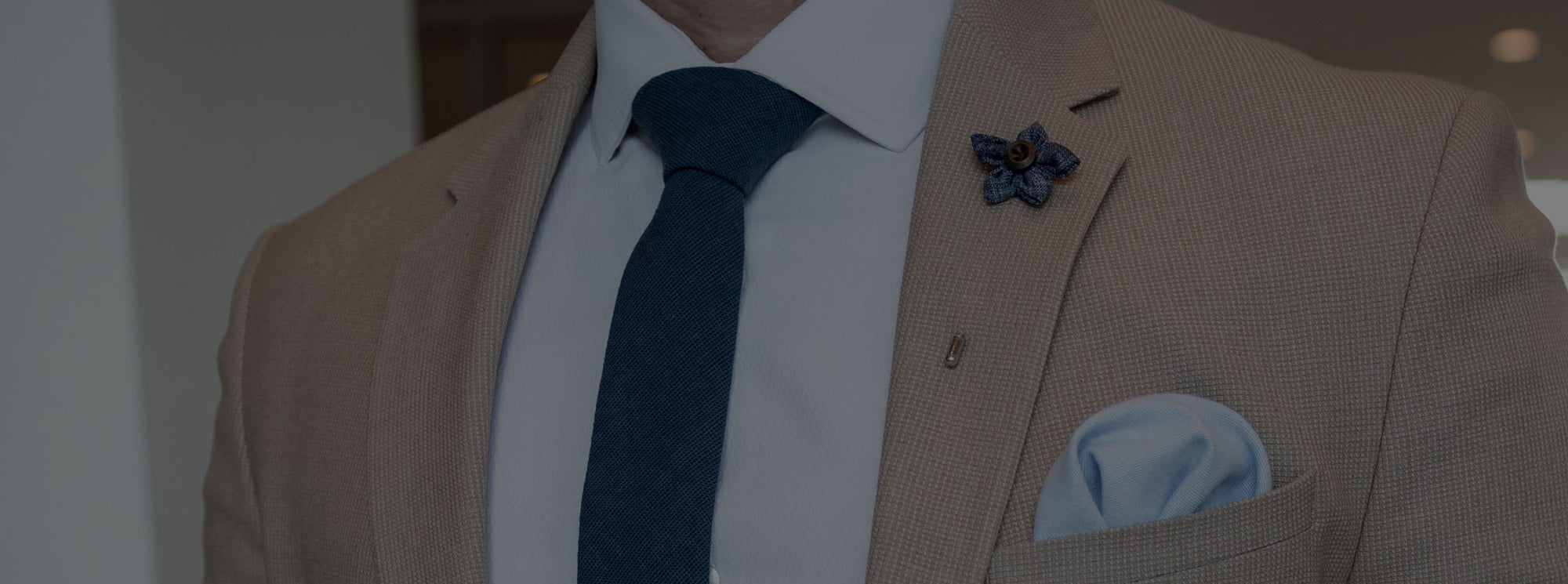 Tan suit with a blue lapel pin
