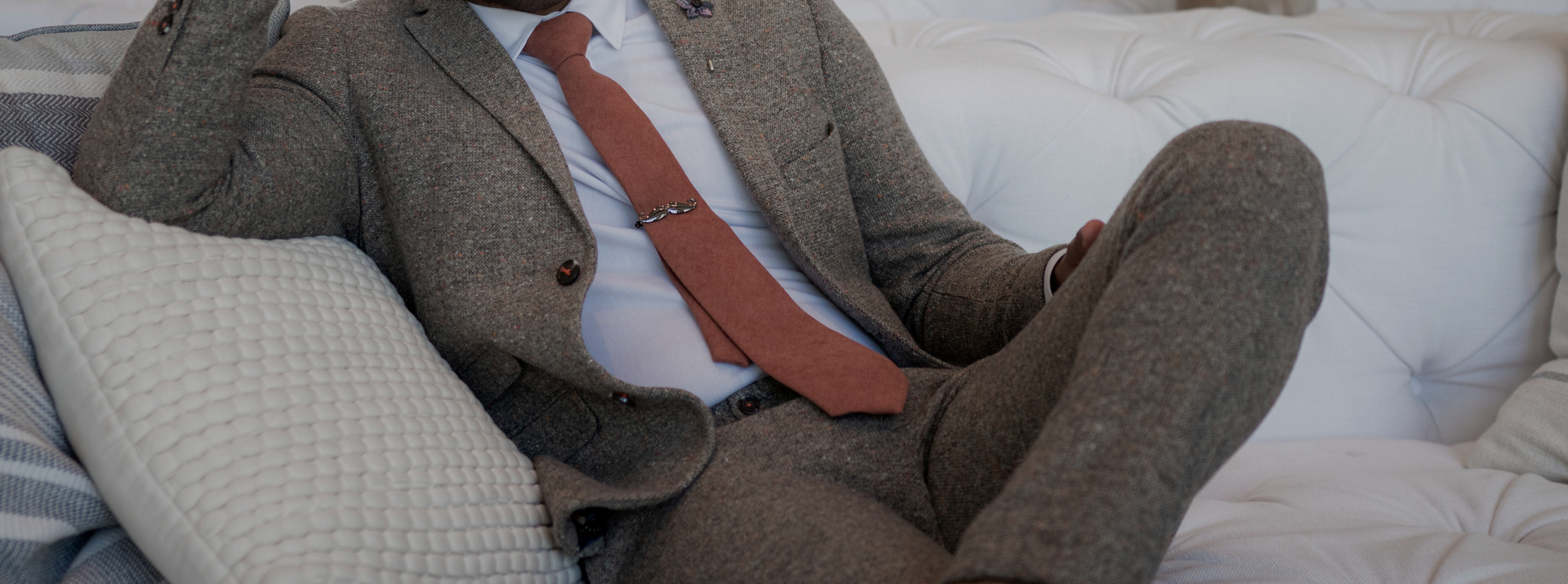 A gentleman sitting on a couch in a brown suit