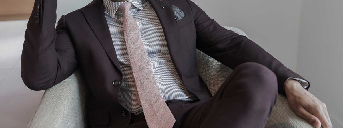 a gentleman in a burgundy suit sitting down