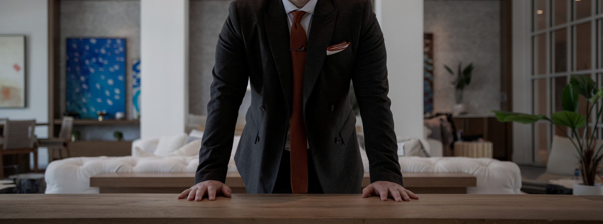 a gentleman leaning on a counter in a charcoal grey suit