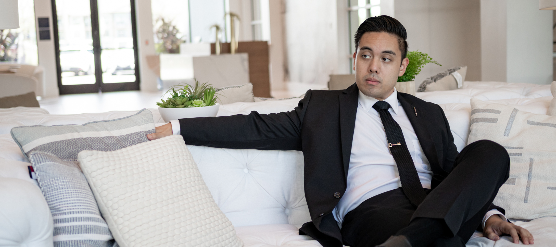 a man sitting down on a couch in a black suit
