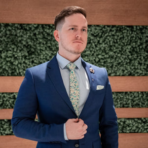 Man wearing Floral Aqua Sea Blossoms Tie Set in front of a foliage wall in a blue suit