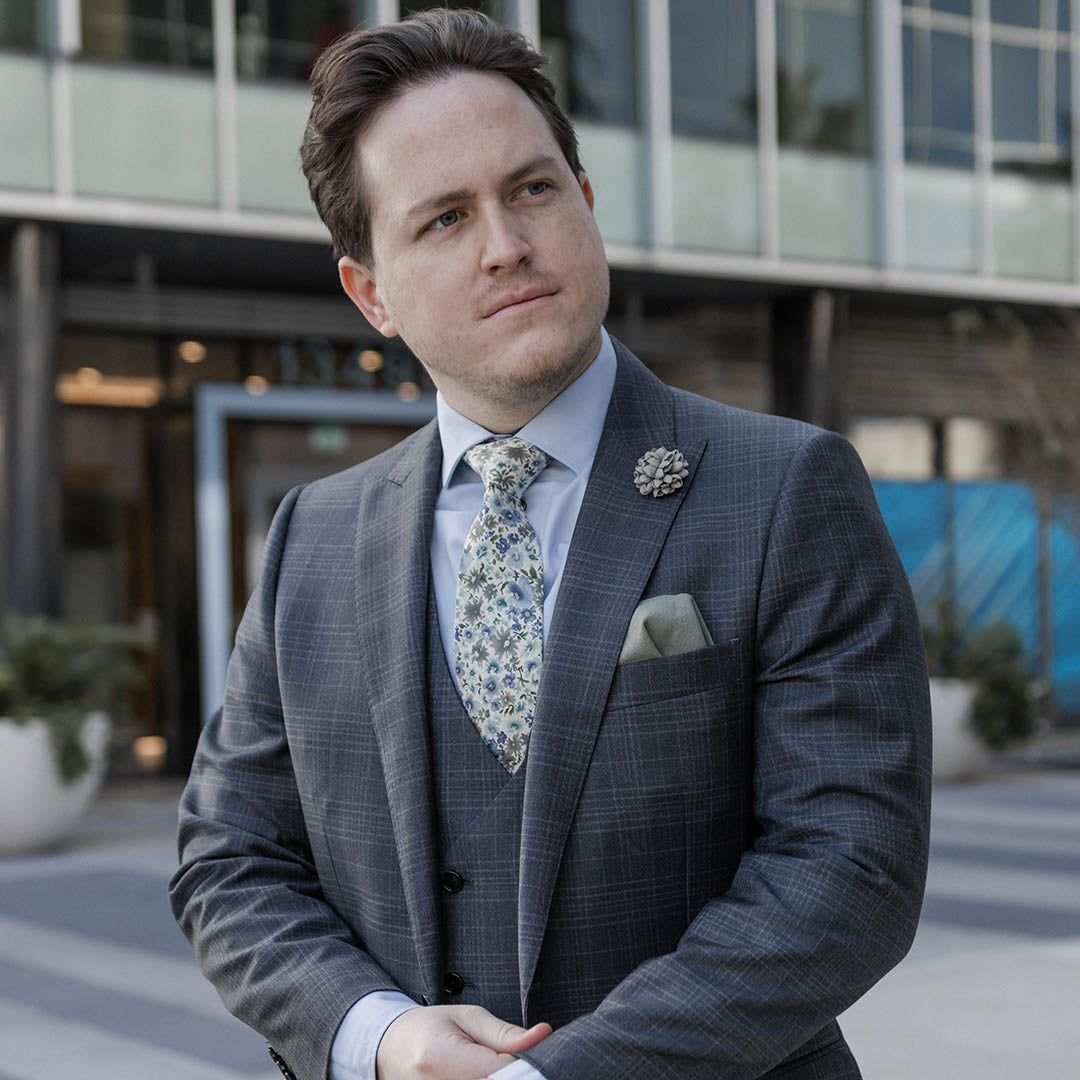 Man wearing a Charcoal grey business suit in an urban environment with a creamy floral tie