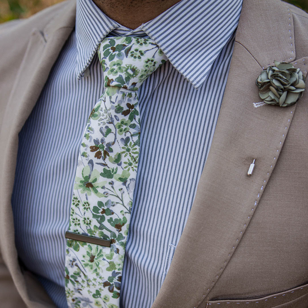 Tan suit with a blue striped shirt and floral green tie on a model closeup shot