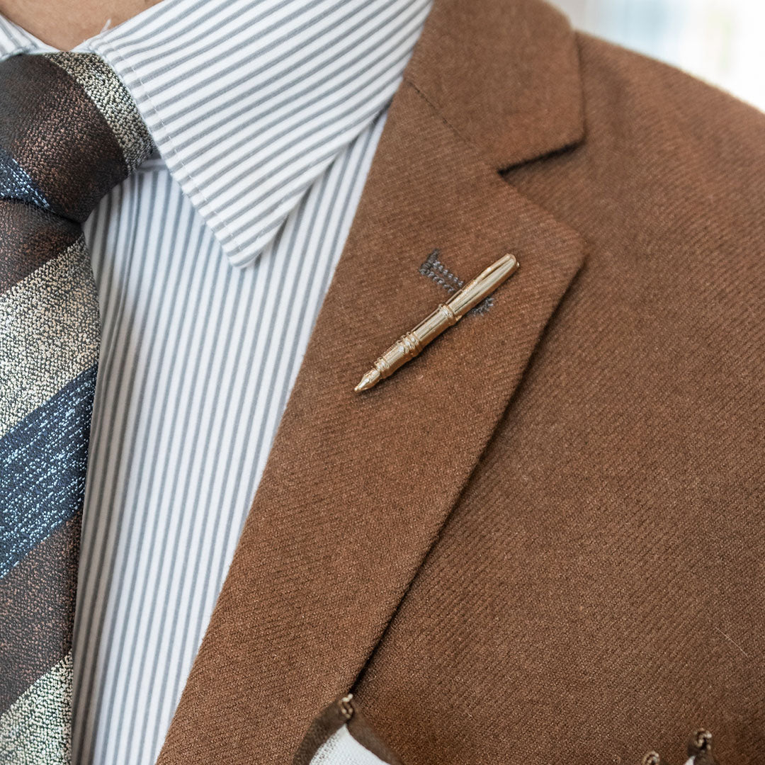 Gold metal lapel pin over brown suit