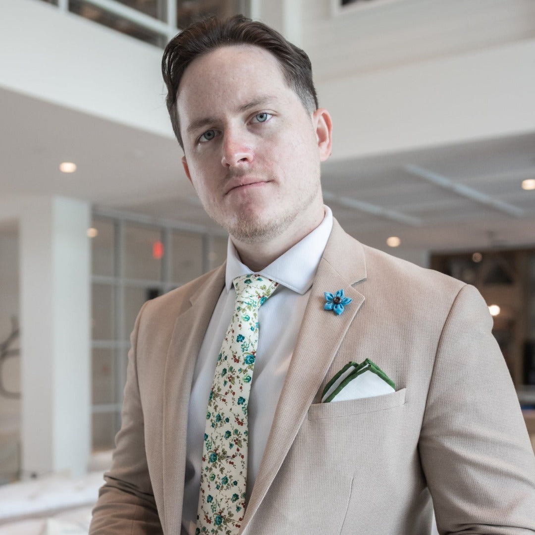 Man wearing the wildflower aqua light blue lapel pin on a tan suit