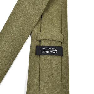 Green tie with 'Art of the Gentleman' label on a white background