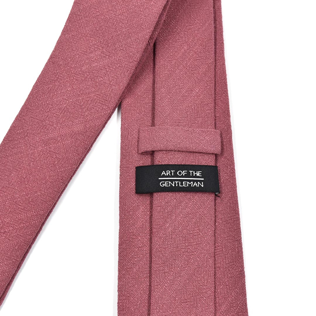 Pink tie with a label reading 'Art of the Gentleman' on a white background