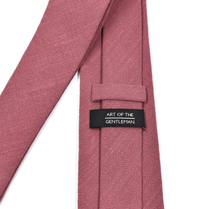 Pink tie with a label reading 'Art of the Gentleman' on a white background
