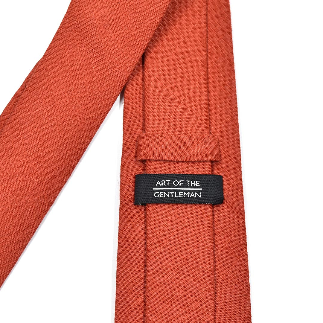 Orange tie with a label reading 'Art of the Gentleman' on a white background