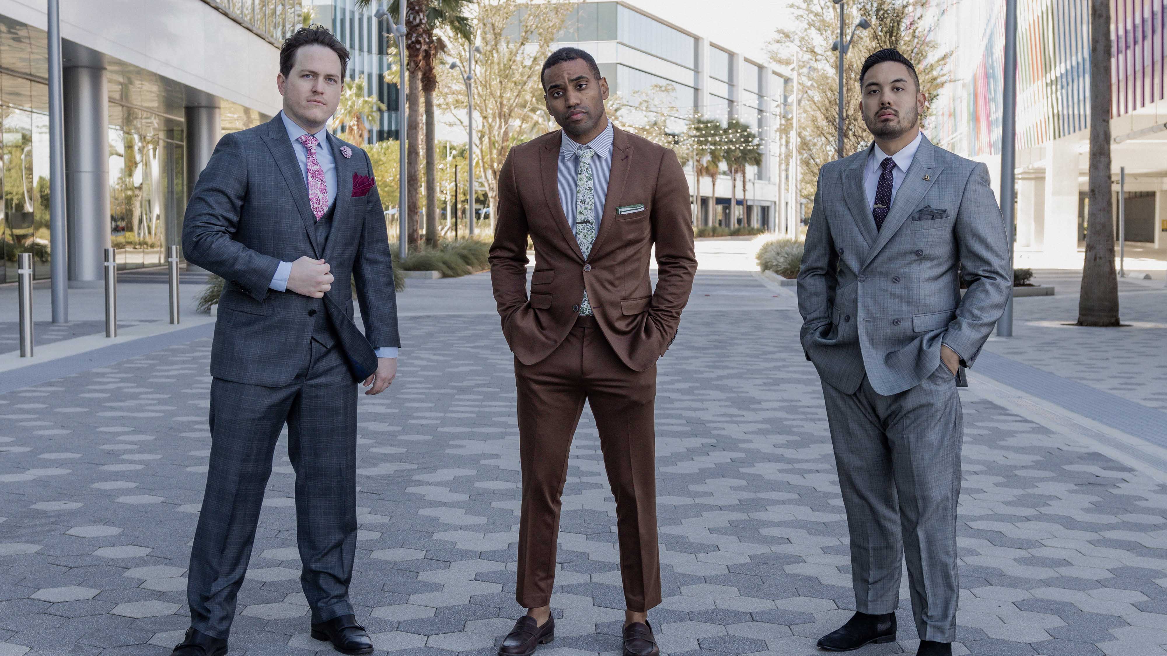 Three men in suits standing on a city street.