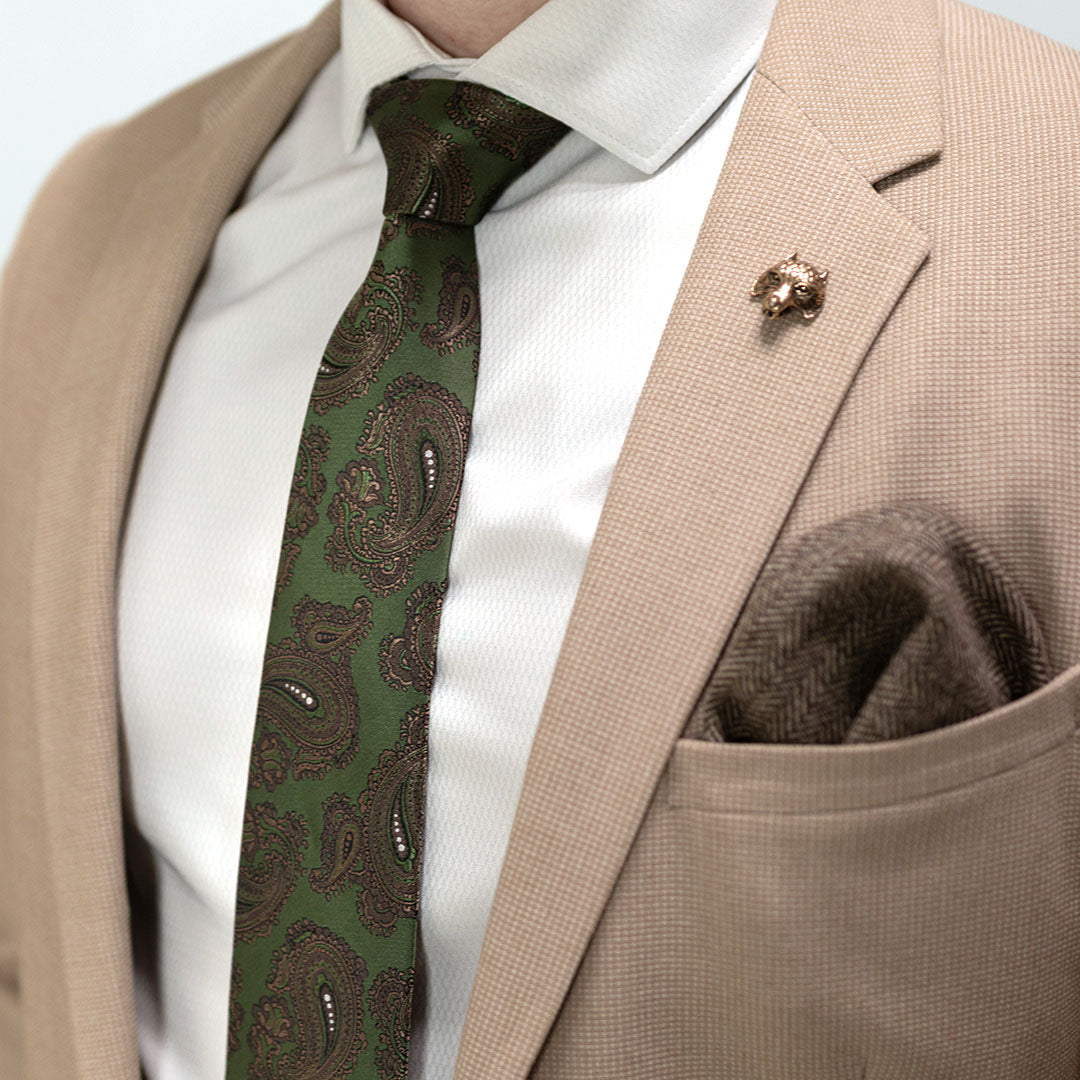 Close-up of a person wearing a beige suit with a green paisley tie and a pocket square.