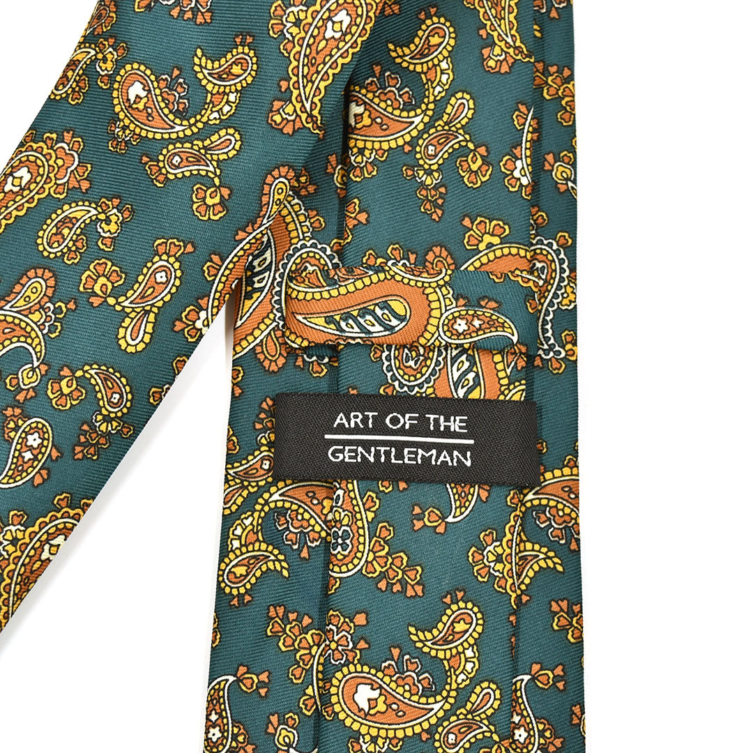 Patterned emerald green tie with 'Art of the Gentleman' label on a white background