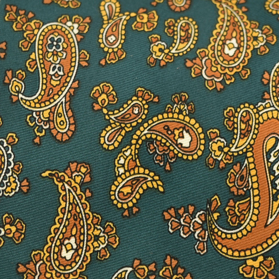 Close-up of a patterned fabric with orange and yellow paisley design on a emerald green background