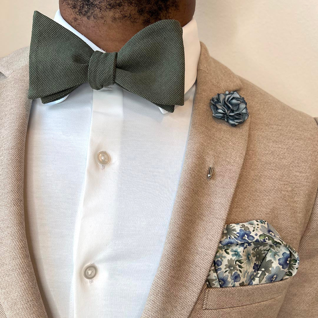 Man wearing a tan suit with the solid olive bow tie set