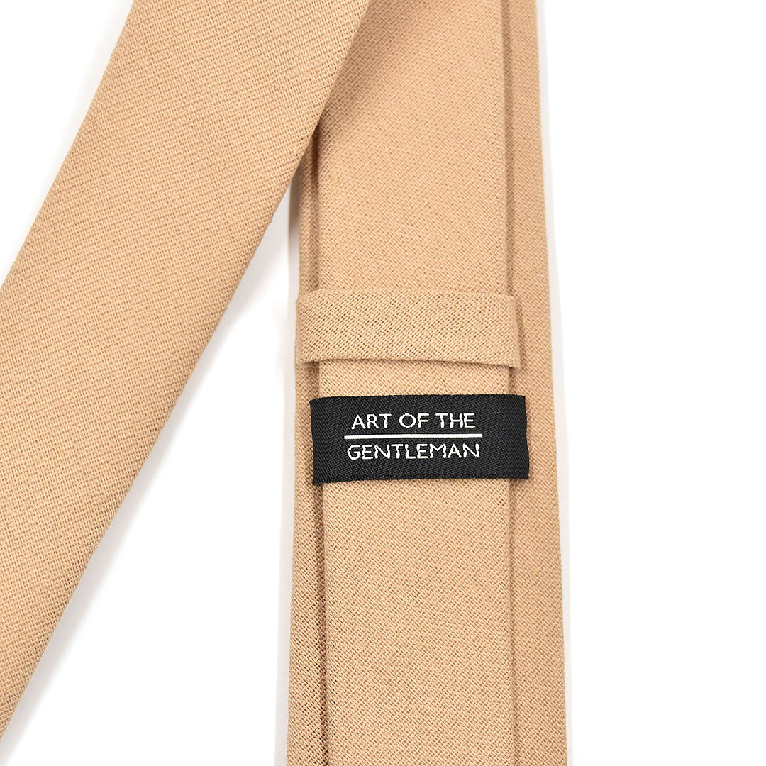 Beige tie with a label reading 'Art of the Gentleman' on a white background