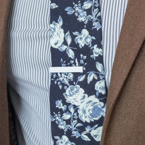 White tie bar over a floral navy tie and striped dress shirt