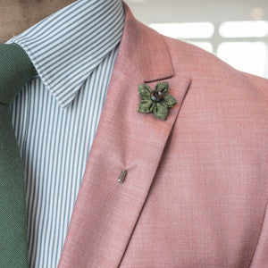 Wildflower deep olive lapel pin over a pink suit lapel