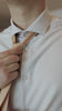 man tieing a knitted sand tie while wearing a tan suit