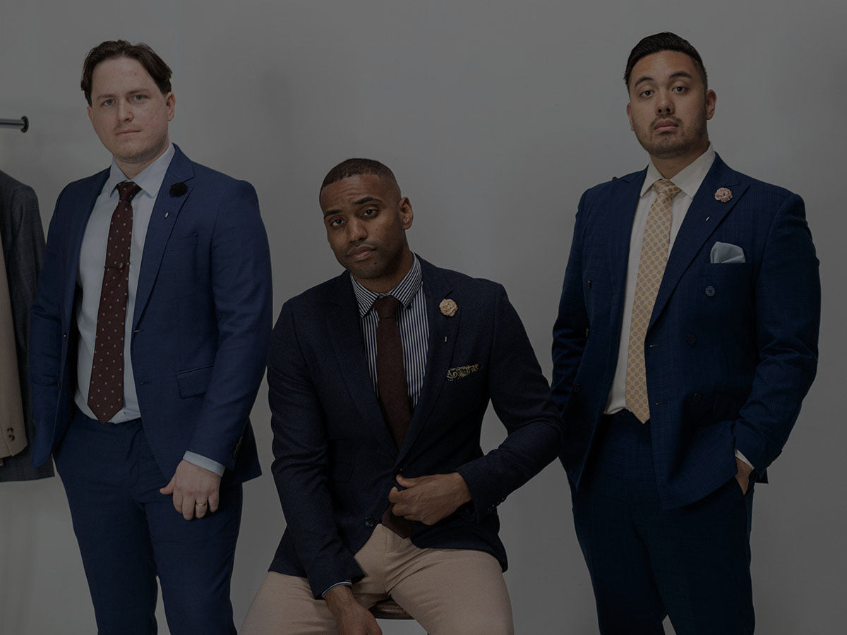 Three men in suits posing against a plain background