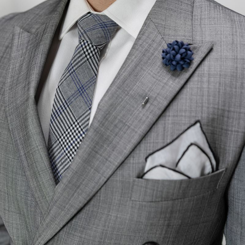 Gray suit with plaid tie and pocket square, close-up of chest area